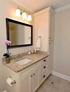 a bathroom with marble counter tops and white cabinets