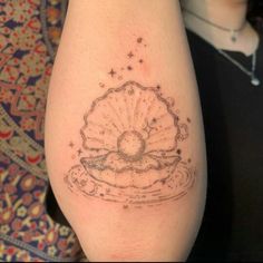 a tattoo on the leg of a person with a sea shell and stars around it