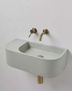 a white sink mounted to the side of a wall next to a faucet