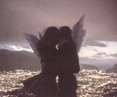 two people are kissing in front of an aerial view at night with lights on the city below