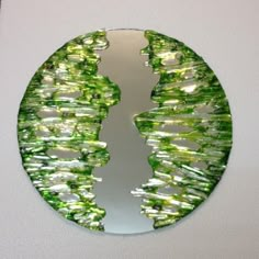 a circular mirror with green and white designs on the side, hanging on a wall