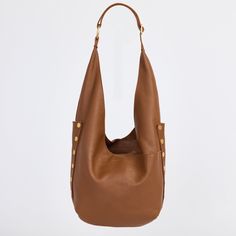 An updated version of everyone's favorite hobo bag has entered the chat; meet our updated Tom. With a zippered main compartment and adjustable strap, this shoulder bag still resembles the original, with pockets galore and a slouchy nature, making it extra roomy and the ultimate catch all bag. This leather features a soft pebbled texture with a hint of shine. Embrace the warm allure of this medium brown hue, enriched with a delicate yellow undertone that adds depth and sophistication to any ensemble. Crafted with a soft pebbled leather with a hint of shine featuring a warm medium brown hue Red logo twill lining Brushed gold hardware, functionality covered for life Exterior: side panels, crisscross drop pockets on front and back panels, adjustable shoulder strap with large O ring, slit detai Versatile Everyday Satchel With Snap Closure, Modern Everyday Bucket Bag With Snap Closure, Versatile Shoulder Bag With Snap Closure For On-the-go, Luxury Hobo Bag For Everyday, Classic Hobo Bag With Snap Closure For Everyday, Modern Everyday Hobo Bag With Snap Closure, Modern Hobo Bag With Snap Closure For Daily Use, Everyday Use Hobo Bag, Daily Use Double Handle Hobo Bag With Snap Closure