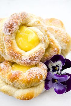 some sugared doughnuts are stacked on top of each other with a purple flower