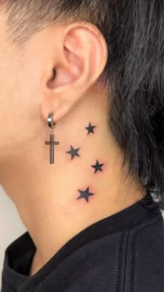 a person with a cross and stars tattoo on their back of the neck, behind his ear