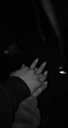 two hands reaching out towards each other in the dark, with one hand holding another