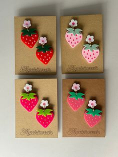 four strawberry shaped magnets sitting on top of a brown paper bag next to each other