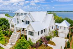 an aerial view of a white house with trees and water in the background