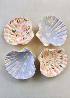 four seashells with flowers painted on them