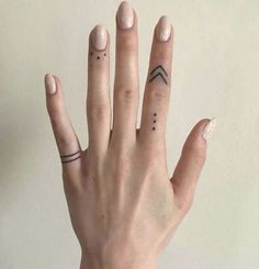 a woman's hand with two small tattoos on her left thumb and one finger