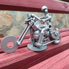 a small metal motorcycle sitting on top of a wooden bench