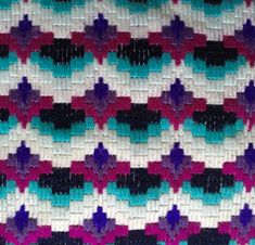 a crocheted blanket is shown with different colors and shapes on the edges, including black, white, blue, pink, and purple