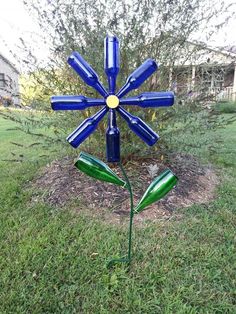 a blue flower made out of wine bottles sitting in the grass