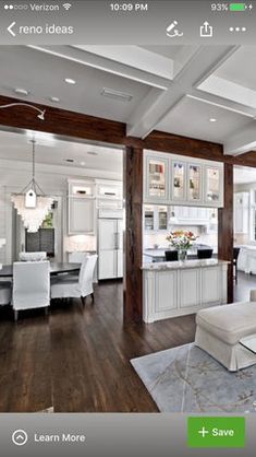 a living room filled with white furniture and wooden flooring next to an open kitchen