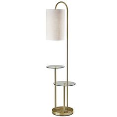 a floor lamp with a white shade on the top and a round glass table below it