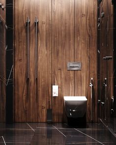 a modern bathroom with wood paneling and black marble flooring on the walls, along with a toilet and bidet