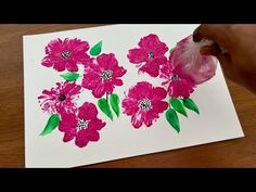 someone is painting pink flowers on white paper