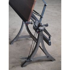 a wooden table with metal legs and a monitor on it's back end, sitting in an empty room