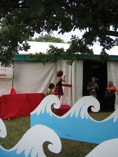 people are standing in front of a tent with surfboards on it and red tarps