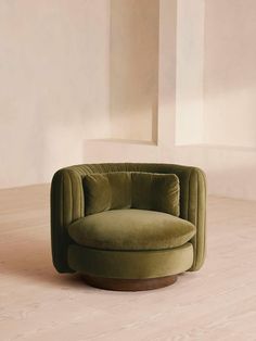 a green chair sitting on top of a hard wood floor next to a white wall