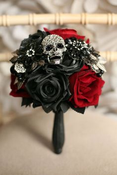 a bridal bouquet with black and red flowers on a chair in front of a bed