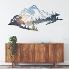 a wooden cabinet sitting in front of a wall with mountains on the top and trees below