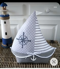 a sailboat shaped pillow sitting on top of a wicker table next to a lighthouse