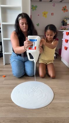 a mother and daughter are playing with an object in the room that looks like a water fountain