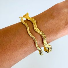 Reflecting the gorgeous movement of the octopus (He'e), this long awaited slim tentacle-inspired bangle is unlike any other. This is a Keani Hawai'i signature design. Shown in the second photo with our original He'e Ho'omana Bangle. 18K heavy gold plated jewelry combines affordability with luxury, providing a stunning appearance similar to solid gold pieces. Its thick gold layer ensures durability, making it resistant to water and light everyday wear. To maintain its brilliance, avoid activities Elegant Snake Shape Bangle Perfect For Gift, Elegant Snake-shaped Bangle For Gift, Elegant Snake Shape Bangle Gift, Gold Bangle Bracelet With Unique Design, Elegant Adjustable Wavy Bangle, Elegant Gold Snake-shaped Bangle, Retail Boutique, The Octopus, Casual Jewelry