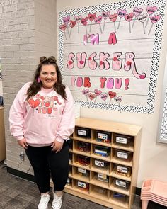 a woman is standing in front of a bulletin board with writing on it and smiling at the camera