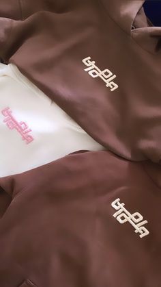 two brown and white hoodies laying on top of each other next to each other