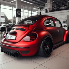 a red vw bug is parked in a showroom