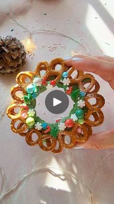 a person is holding a ring made out of pretzels and other items on a table