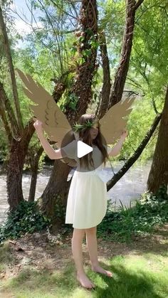 a girl in a white dress is holding up an angel cutout with her hands