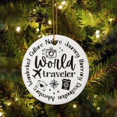 a white ornament hanging from a christmas tree with the words world traveler on it