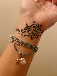 a woman's arm with three bracelets and a starfish tattoo on it