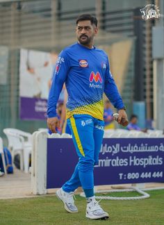 a man in blue and yellow uniform walking on the grass with his foot propped up