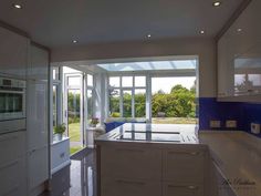 an empty kitchen with white cabinets and blue glass doors that lead to the outside patio