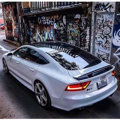 a white car parked in front of a graffiti covered building on the side of a street