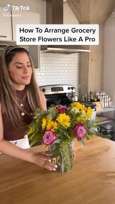 a woman arranging flowers in a vase on top of a wooden table with the words how to arrange grocery store flowers like a pro