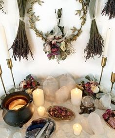 a table topped with lots of candles next to flowers and wreaths on the wall