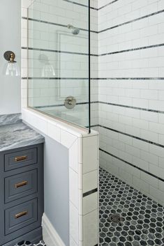 a white bathroom with black and white floor tiles on the shower wall, vanity sink and mirror