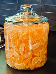 a glass jar filled with orange slices on top of a counter