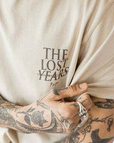 a man with tattoos on his arm holding onto a t - shirt that says the lost years