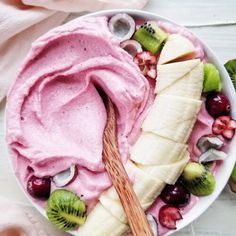 a bowl filled with fruit and yogurt next to sliced kiwis