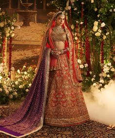 Exuding sovereign grace, our signature sindoori red lehenga is adorned with intricate gold zari and enhanced by dabka, nakshi, and delicate mukaish work. Paired with a fully sequined gold blouse, a contrasting purple bandhej dupatta, and artfully crowned with a richly embellished organza veil, this ensemble is an ode to regality. Luxury Red Unstitched Lehenga, Manish Malhotra Wedding Lehenga, Red Bridal Lehenga Manish Malhotra, Abhinav Mishra Red Lehenga, Manish Malothra Lehenga, Organza Veil, Manish Malhotra Lehenga, Fancy Lehenga, Indian Wedding Outfit