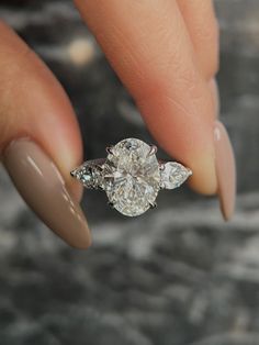 a woman's hand holding a diamond ring with two diamonds on the middle finger