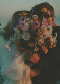 a man and woman embracing each other with flowers in their hands