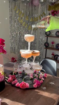 a table topped with lots of wine glasses filled with liquid and flowers on top of it