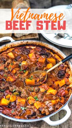 a large pot filled with beef stew on top of a wooden table next to silverware