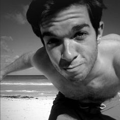 a shirtless man on the beach posing for a photo